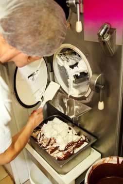 Kadın şef ve işçi çalışıyor dondurma fabrika Ice cream maker Makina gelen dondurma pisliği temizliyor. Dondurma hazırlanması.