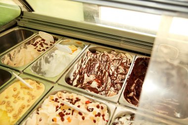 Bar lezzetli dondurma yaz Satılık çok tatlar ile. Buzdolabı çelik konteyner hizmet içinde çikolata sos ile kremsi vanilyalı dondurma ile. Şekerli tatlı öğeleri dekorasyon ile.