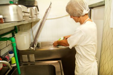 Kadın şef ve işçi çalışıyor dondurma fabrika pastörize süt dökme ve pastörizasyon makine hazırlama bazında Dondurma üretimi için karıştırma süt pişirme. Dondurma hazırlanması.
