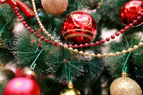 Πρωτοχρονιάτικα πολύχρωμα διακοσμητικά στολίδια σε χριστουγεννιάτικο δέντρο. Δωμάτιο διακοσμημένο με χριστουγεννιάτικη γιορτή, σκηνή διακοπών με διάφορα σχήματα, πολύχρωμες μπάλες, διακοσμητικά τόξα λάμψη και πουλί στο δέντρο. — Φωτογραφία Αρχείου