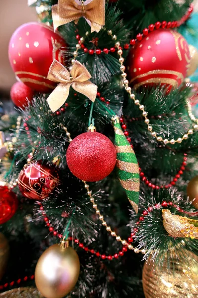 Decorazioni colorate di Capodanno sull'albero di Natale. Camera decorata per la celebrazione del Natale, scena di festa con varie forme, palline multicolori, fiocchi decorativi scintillanti e uccello sull'albero . — Foto Stock