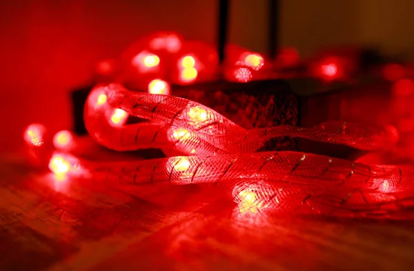 Bright red New Year and Christmas rice lights, shallow depth of field. Abstract red light background. Decorative flashing lights, ornaments to christmas celebration, holiday scene. Christmas concept.