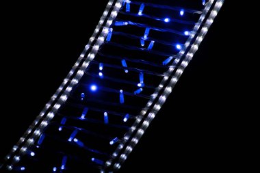 Noel dekoratif mavi ve beyaz yanıp sönen ışıkların bir parçası, kapat. Yeni yılın sokak ayrıntıları ve Noel süslemeleri, ipli pirinç lambaları. Noel kutlaması için süsler, tatil sahnesi.