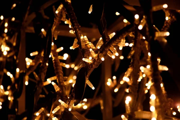 Teil der Weihnachtsdekoration gelb, golden, weiß blinkende Lichter, Nahaufnahme. Detail der Neujahrs- und Weihnachtsdekoration, Reislicht-Glühbirnen. Schmuck zur Weihnachtsfeier, Feiertagsszene. — Stockfoto