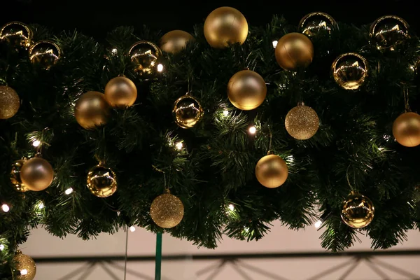 Παραδοσιακά στολισμένα Χριστουγεννιάτικα στολίδια σε στεφάνι από πράσινο έλατο ή έλατο κλαδιά και λαμπερή γιρλάντα σε εξωτερικούς χώρους. Twigs πεύκο, χρυσό και ασήμι μπάλες Χριστούγεννα ως διακόσμηση για τις διακοπές της Πρωτοχρονιάς. — Φωτογραφία Αρχείου