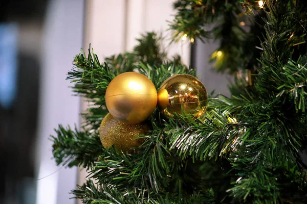Le bagattelle decorate tradizionali pendono su ramoscelli verdi di pino. Luminose palline d'oro su albero di Natale di abete o abete rosso con lampadine di luci di riso stringa. Ornamenti per la celebrazione di Natale, scena delle vacanze . — Foto Stock