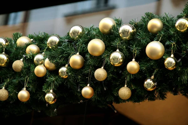 緑のモミやトウヒの枝や屋外で輝くガーランドで作られた花輪に伝統的な装飾されたクリスマスの泡。正月の飾りとして松、金、銀のクリスマスボール. — ストック写真