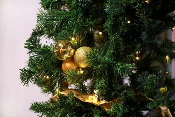 Boules décorées traditionnelles suspendues sur des brindilles vertes arbre de pin. Boules d'or brillant sur sapin ou épicéa de Noël avec des ampoules de riz à cordes. Ornements pour la célébration de Noël, scène de vacances . — Photo