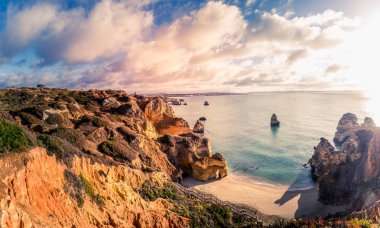 güzel Atlantik Okyanusu görünümü ufuk ile kumlu plaj, kayalar ve güneş doğarken dalgalar. Algarve, Portekiz