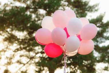 Pembe ve beyaz helyum balonları yeşillik ve gökyüzü arka plan üzerinde büyük bir demet