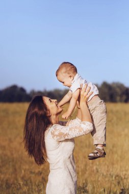 Güzel anne gülen oğlu havaya atar. Ön plan üzerinde odaklanmak.