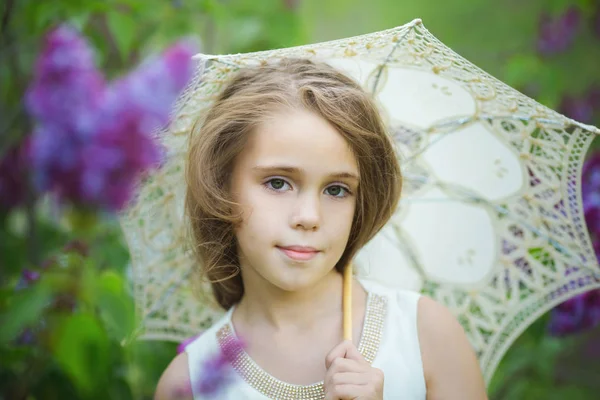 Retrato de primavera romântico de menina bonita jovem em um vestido branco com guarda-chuva de renda em flores lilás — Fotografia de Stock