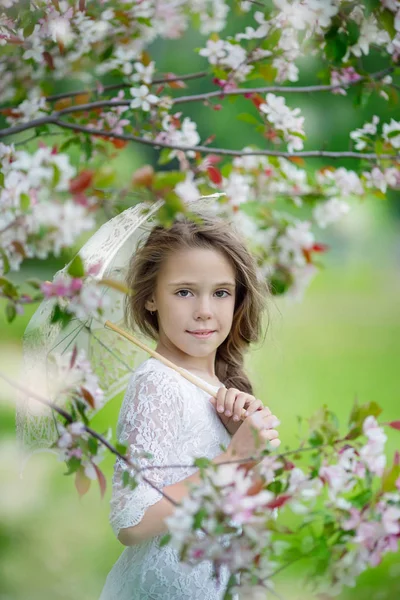 Весенний портрет молодой красивой девушки в белом платье с кружевным зонтиком в яблочном цвете — стоковое фото
