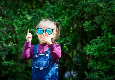 Gözlük ve cathon gelen bir sarafan bir çocuk. Küçük bir model. Moda. Kız açık havada poz
