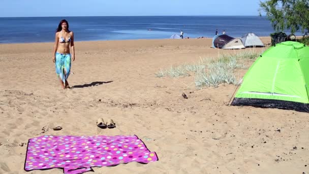 A menina toma banho de sol em um tapete na praia — Vídeo de Stock