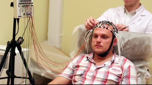 Доктор ставить людину на головний пристрій для електроенцефалографії — стокове відео