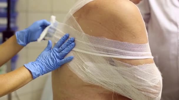 Doctor bandaging a gloved hand of a patient with a bandage — Stock Video