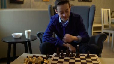 Teen satranç taşları tahta üzerinde koyar.