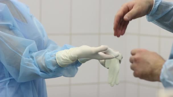 Enfermera ayuda al médico a ponerse guantes médicos blancos — Vídeo de stock