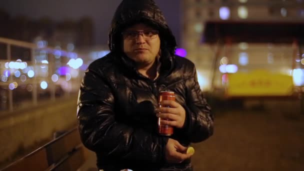 Человек пьет пиво из банок и ест чипсы на улице — стоковое видео