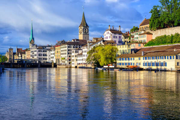 Old town of Zurich with iconic Clock Tower reflecting in Limmat river, Switzerland