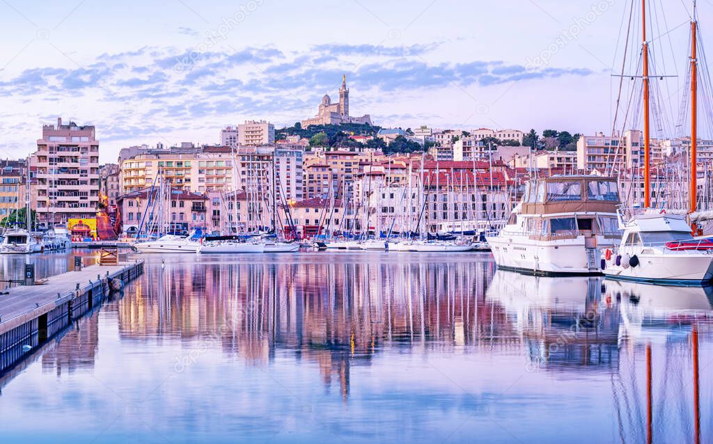 The old Vieux Port and Basilica Notre Dame de la Garde in the historical city center of Marseilles, France, in the early morning light