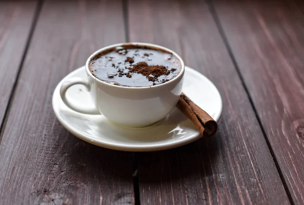 Sebuah foto dengan secangkir cokelat panas di permukaan kayu gelap dihiasi dengan tongkat kayu manis — Stok Foto