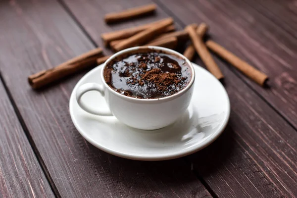 Secangkir cokelat panas pada permukaan kayu gelap dihiasi dengan tongkat kayu manis — Stok Foto