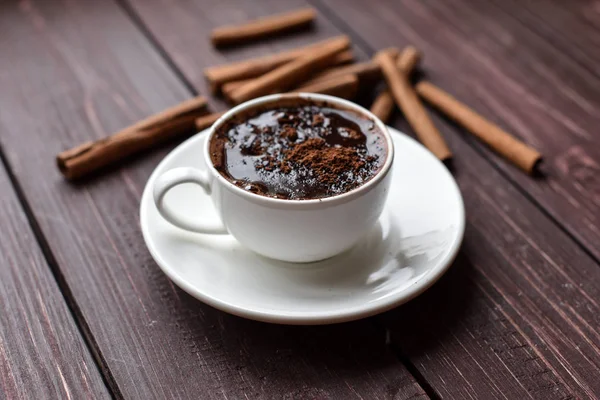 A cup of hot chocolate on a dark wooden surface decorated with cinnamon sticks Royalty Free Stock Photos