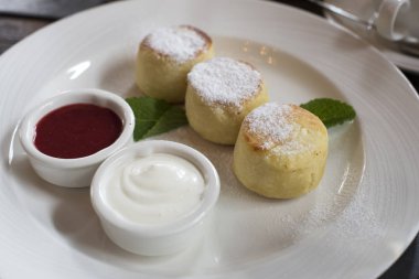 Bir tabak peynirli kek krem sos ve bir kahvaltı masasında reçel ile