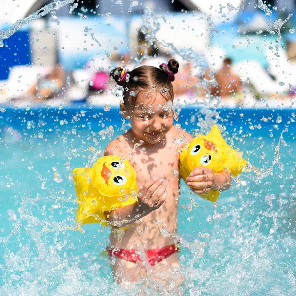 Güneşli bir fotoğraf gülümseyen küçük bir kızın zevk oynamak ve açık havuzda — Stok fotoğraf