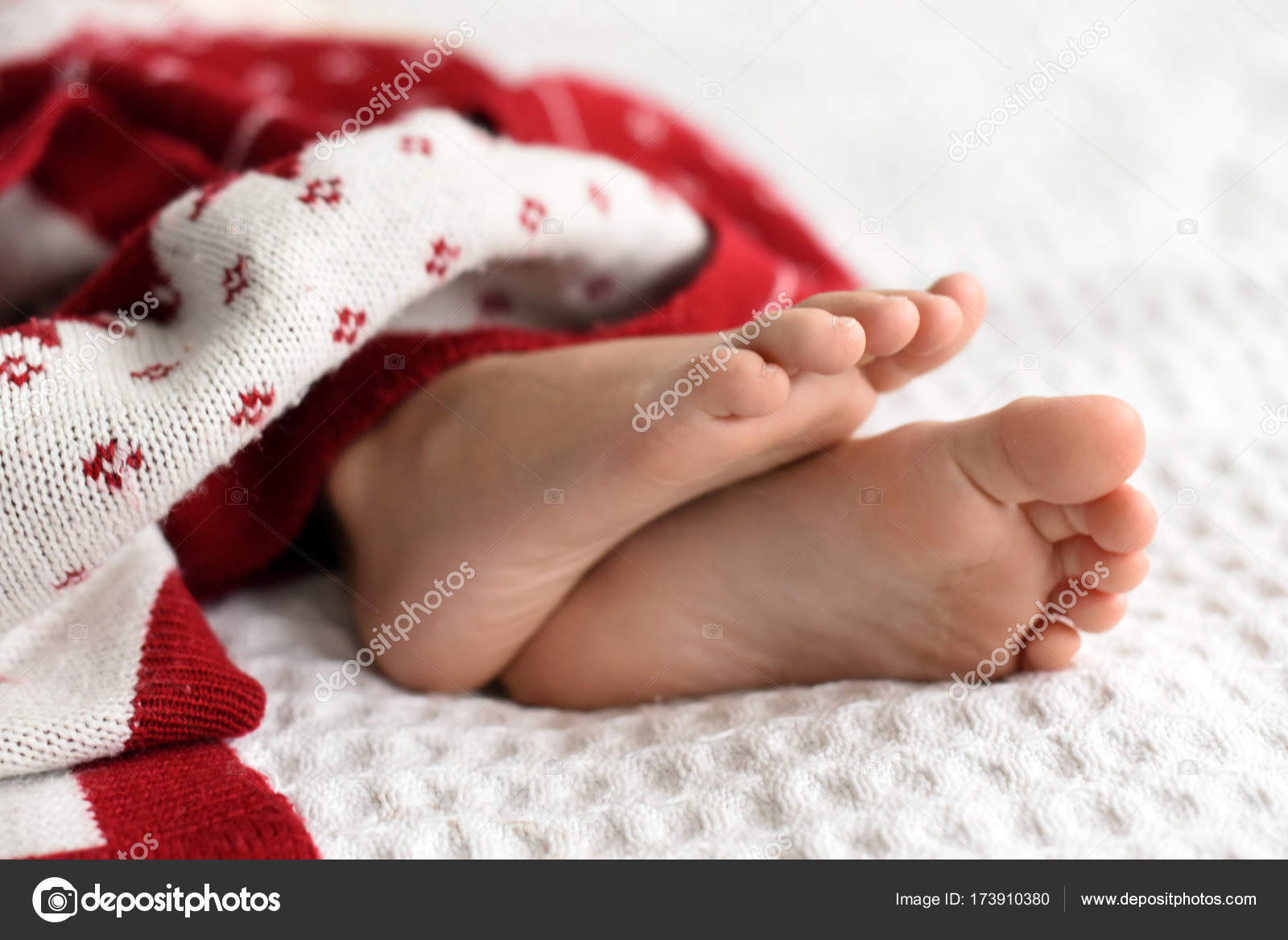 A little child`s feet sleeping under the bright red and white knitted  blanket Stock Photo by ©5231342.gmail.com 173910380
