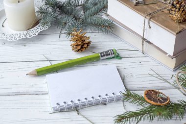 Festival kış sahte bir köknar ile fotoğraf kadar dal, bir açılan not defteri, eski bir kitap, kalem, koniler, bir mum ve decation öğeleri