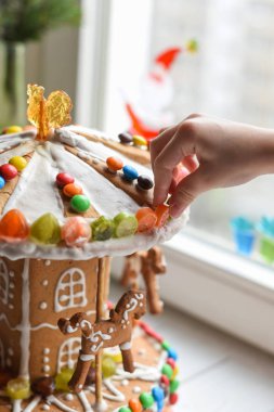 Bir çocuk eller el yapımı gingerbread carousel renkli şekerler ile dekorasyon  