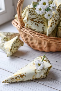 Bir ışık fotoğraf birçok küçük güzel bir sepet, taze çiçek ve çikolata şeker Beyaz ahşap yüzeye sunar.