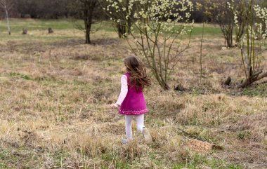 Bir bahar temsil eden bir fotoğraf veya / ve özgürlük kavramı; sırtında çimen üzerinde kamera için çalışan küçük bir kız