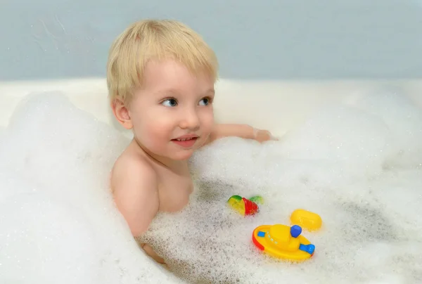 Un enfant se baigne dans une baignoire . Photo De Stock