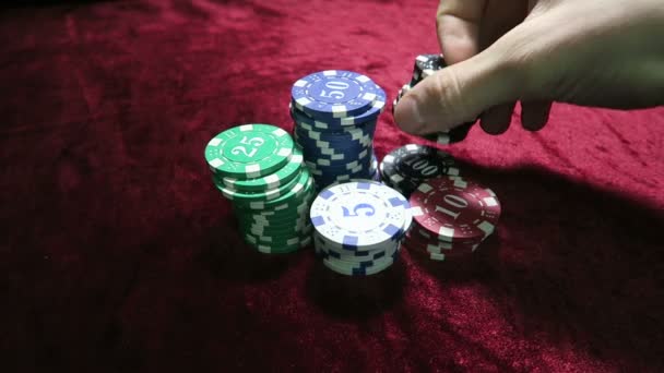 Παιχνίδι του πόκερ. εξιστόρηση το τσιπ στο χέρι του. βρίσκονται γύρω από τις μάρκες. το παιχνίδι είναι σε ένα κόκκινο πανί τραπέζι βελουτέ. — Αρχείο Βίντεο
