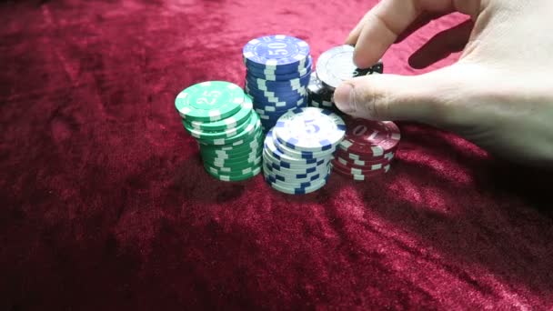 Παιχνίδι του πόκερ. εξιστόρηση το τσιπ στο χέρι του. βρίσκονται γύρω από τις μάρκες. το παιχνίδι είναι σε ένα κόκκινο πανί τραπέζι βελουτέ. — Αρχείο Βίντεο