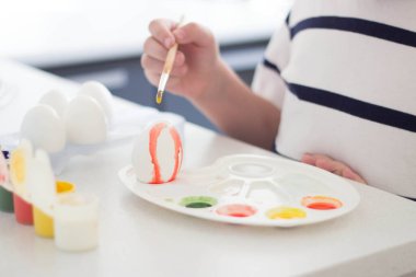Bir çocuk suluboya ve guaj ile yumurta boyar Paskalya 'yı bekler ve oynar