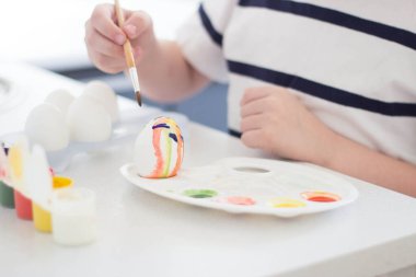 Bir çocuk suluboya ve guaj ile yumurta boyar Paskalya 'yı bekler ve oynar