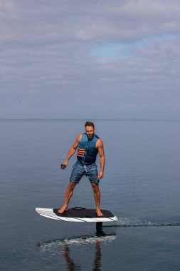 Bir gölde elektrikli folyo üzerinde can yeleğiyle uçan bir adam.