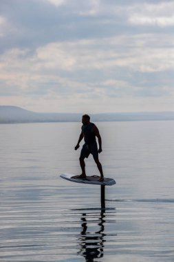 Bir gölde elektrikli folyo üzerinde can yeleğiyle uçan bir adam.