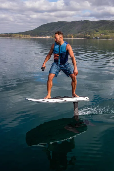 Man riding an electric hydrofoil foil board on a lake with a life jacket — Stock Photo, Image