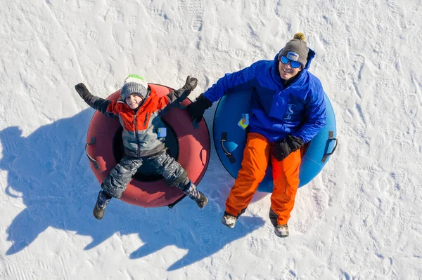 Father and son snow tubing in the winter in Canada