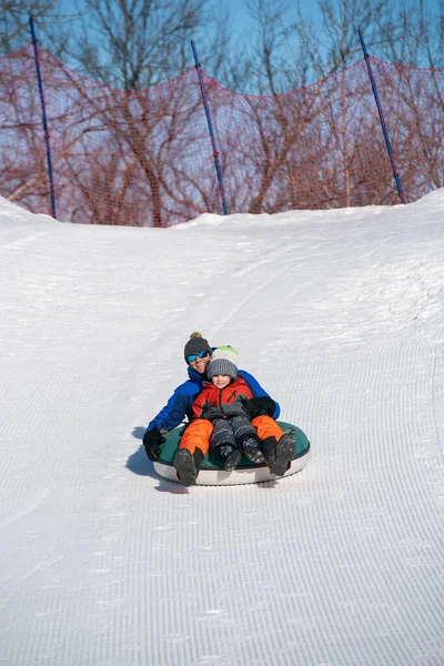 Father and son snow tubing in the winter in Canada