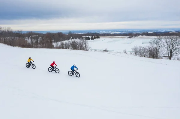 Foto aerea drone di un gruppo di amici in sella alla loro fat bike sulla neve in Ontario, Canada Foto Stock Royalty Free