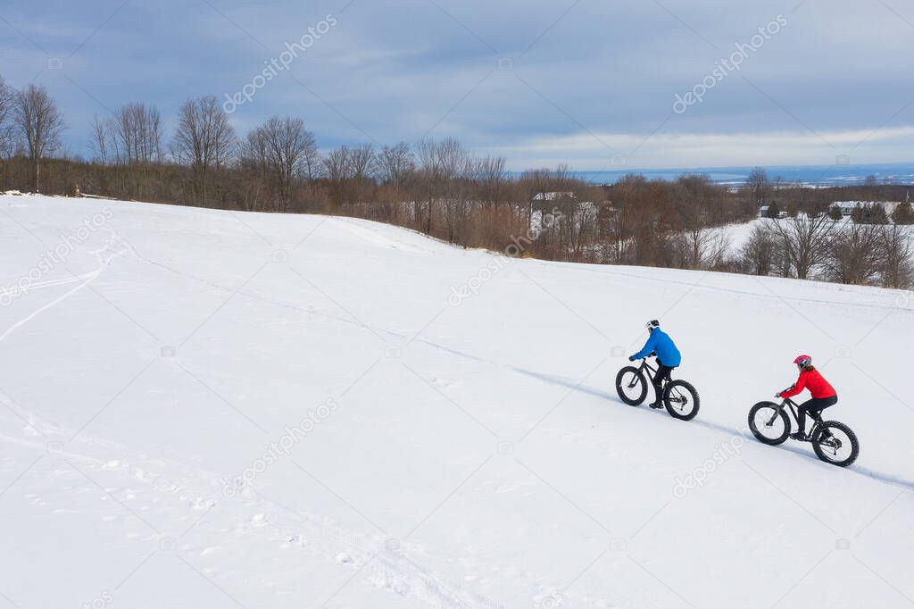 Aerial drone photo of a couple of friends riding their fat bike in the snow in Ontario, Canada