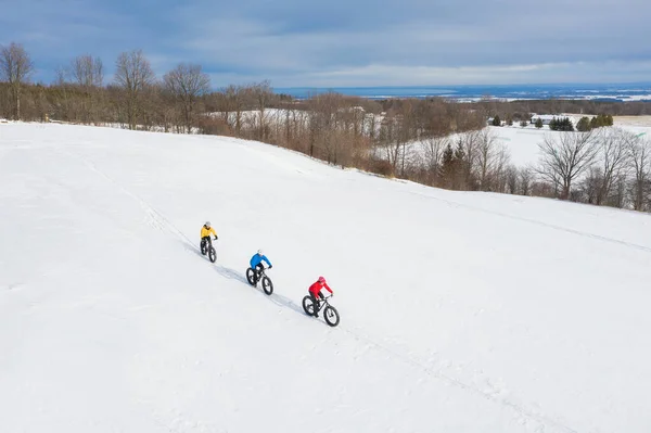 Foto aerea drone di un gruppo di amici in sella alla loro fat bike sulla neve in Ontario, Canada Fotografia Stock