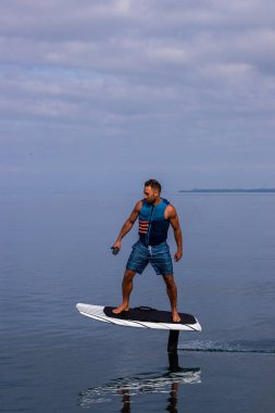 Bir gölde elektrikli folyo üzerinde can yeleğiyle uçan bir adam.